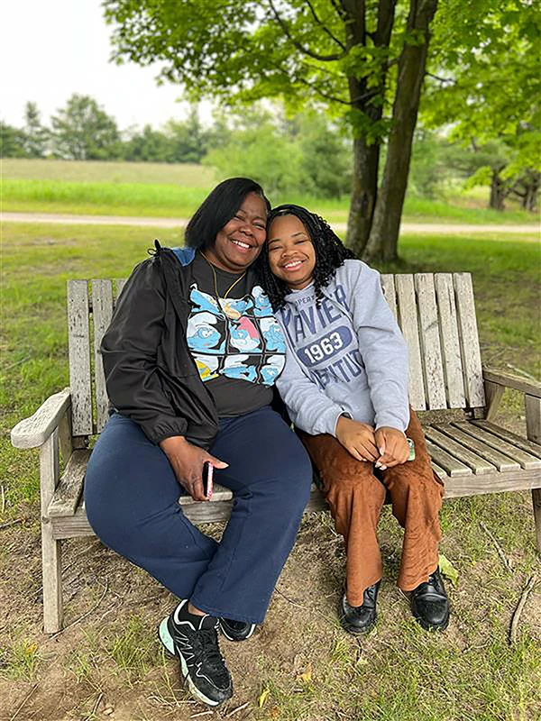 Two smiling people sitting together on a wooden bench outdoors.