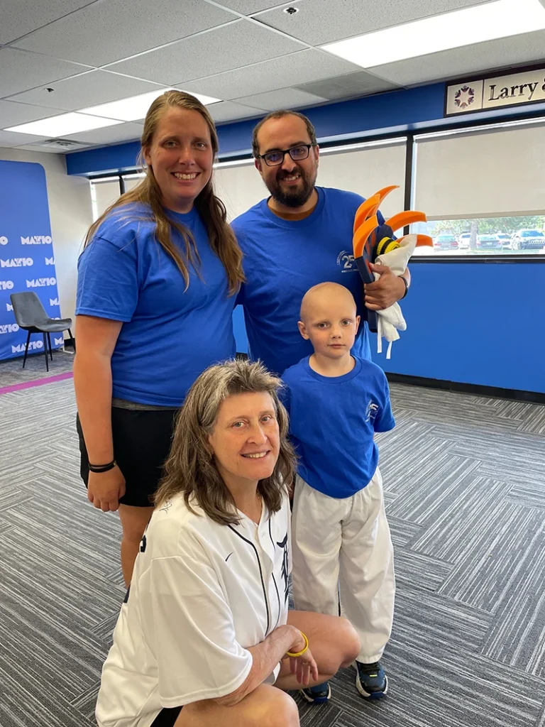 Group of three adults and one child posing in martial arts studio.
