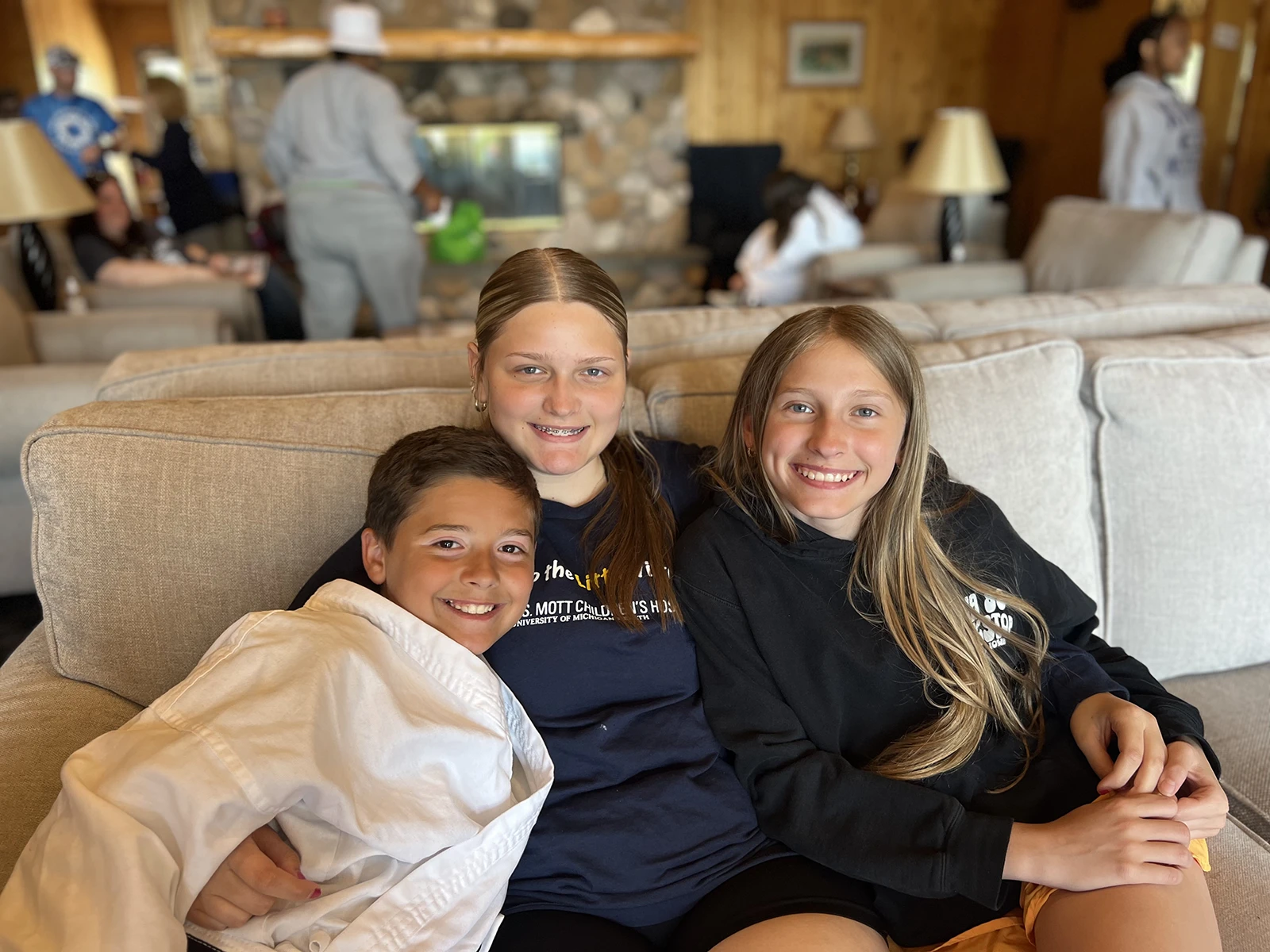Three smiling kids sitting together on a couch.
