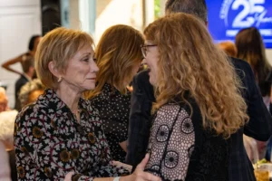 Two women smiling and talking at an event.